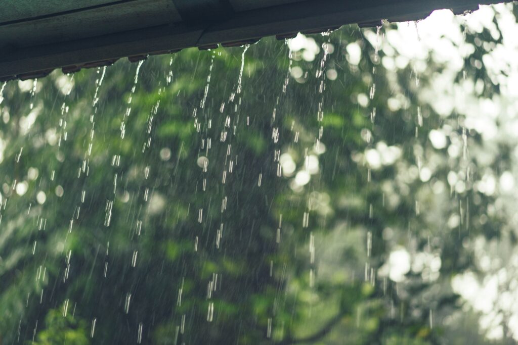 Water droplets falling from a roof during rainfall, illustrating rainwater harvesting.