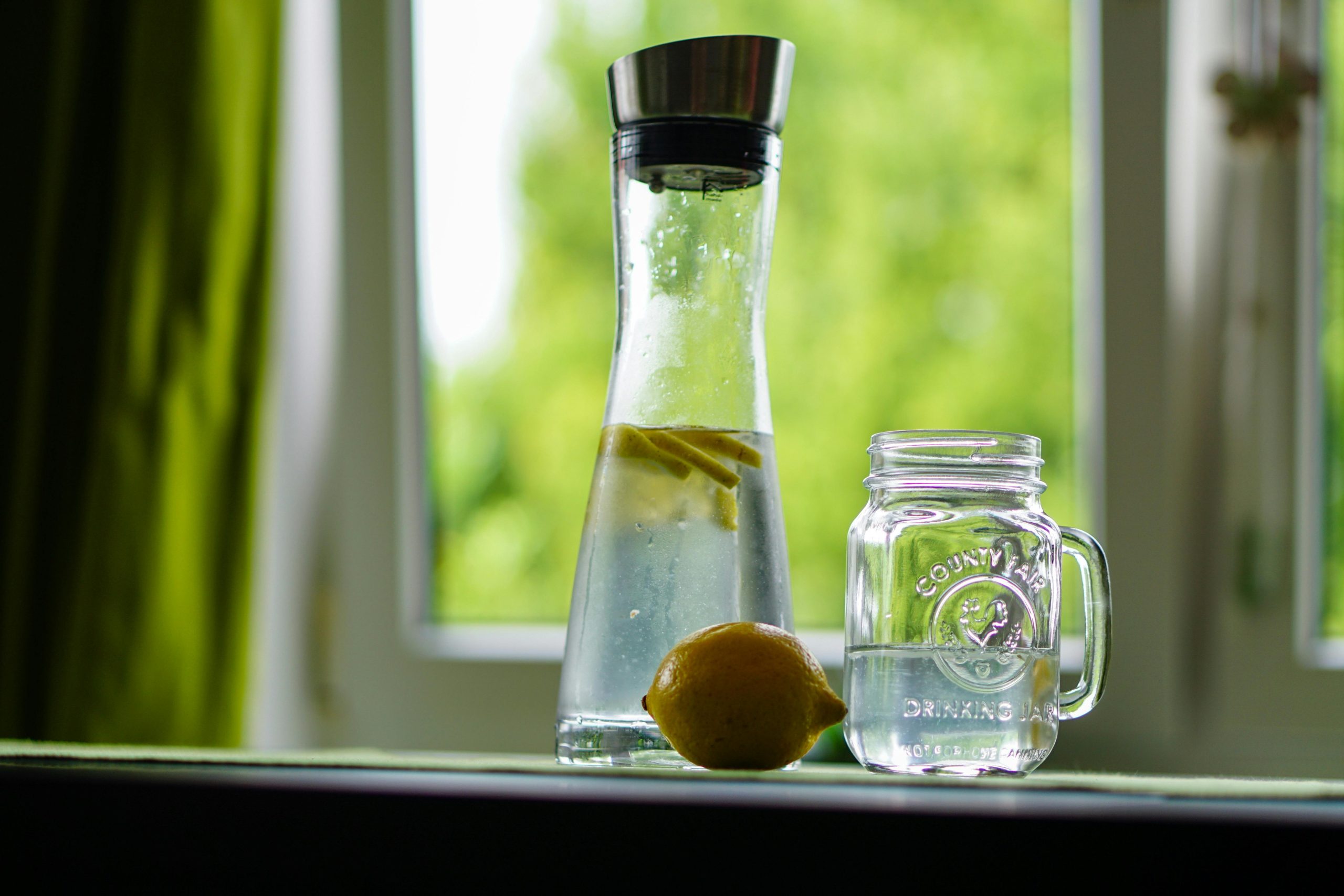 Clear water in glass bottles with a fresh lemon on a ledge, supporting water security themes for Johannesburg borehole solutions.